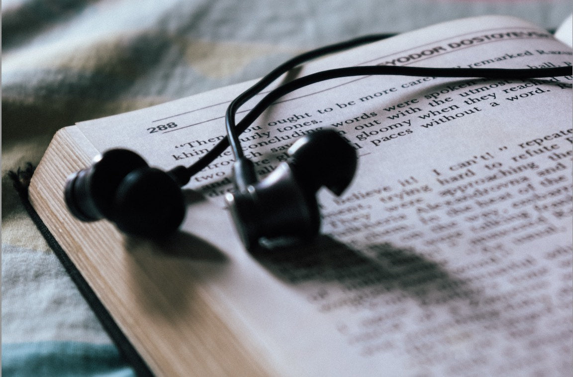 Black earbuds lie across an open book.