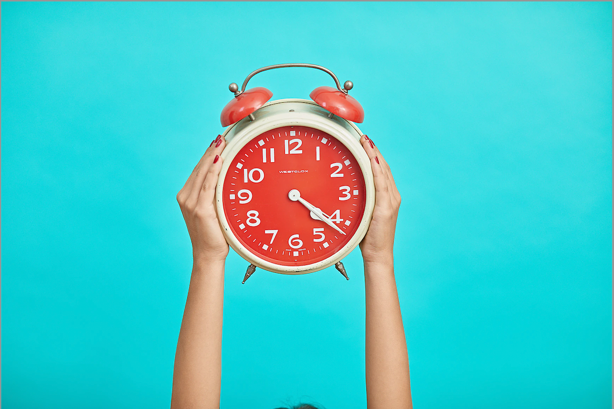 Child's hands holding an alarm clock.