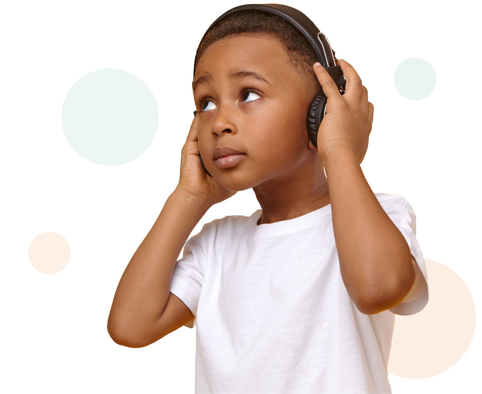 Young boy listening to headphones looking thoughtfully into the distance.