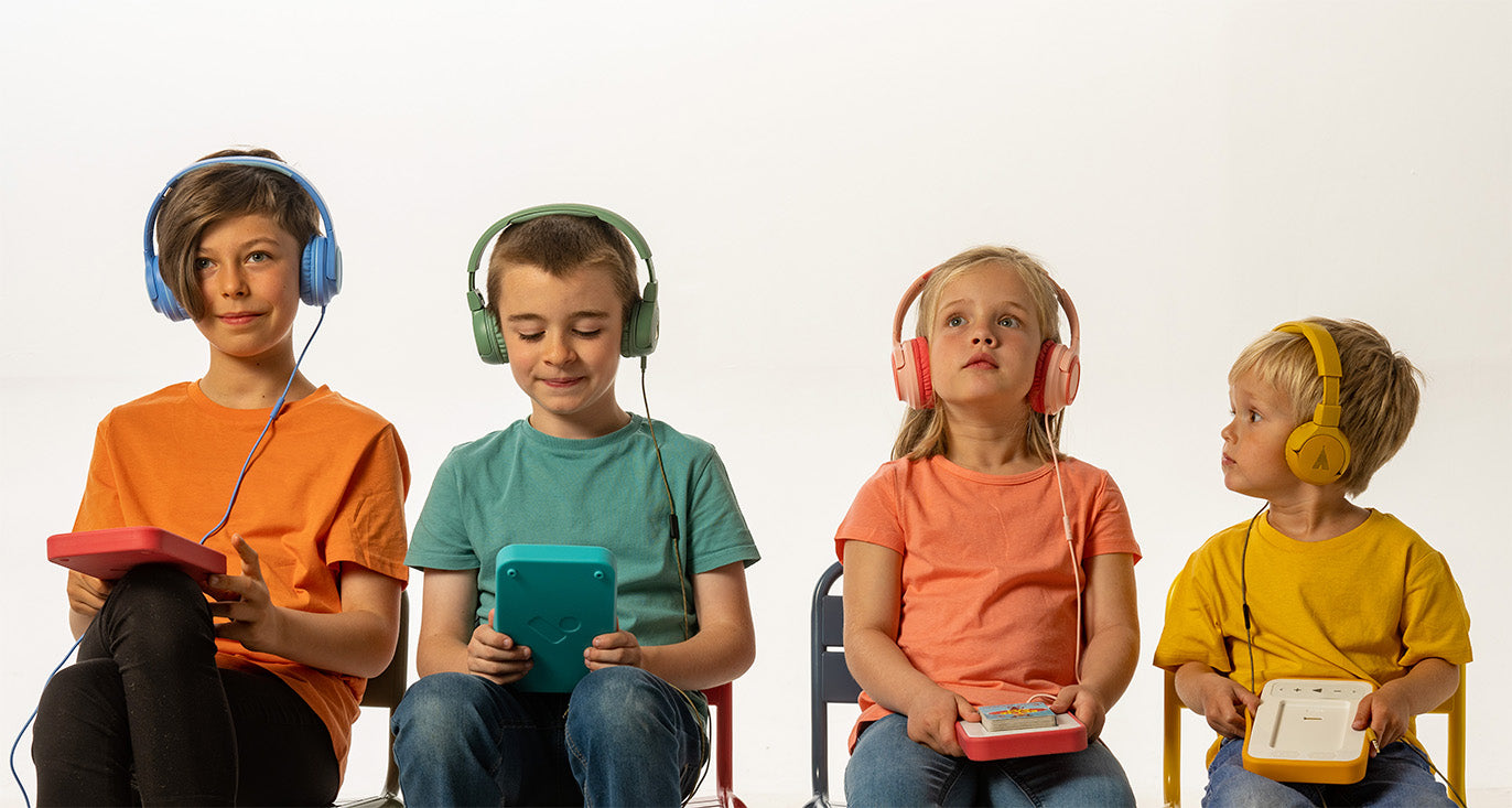 Four children wear headphones, holding Voxblock audiobook players.