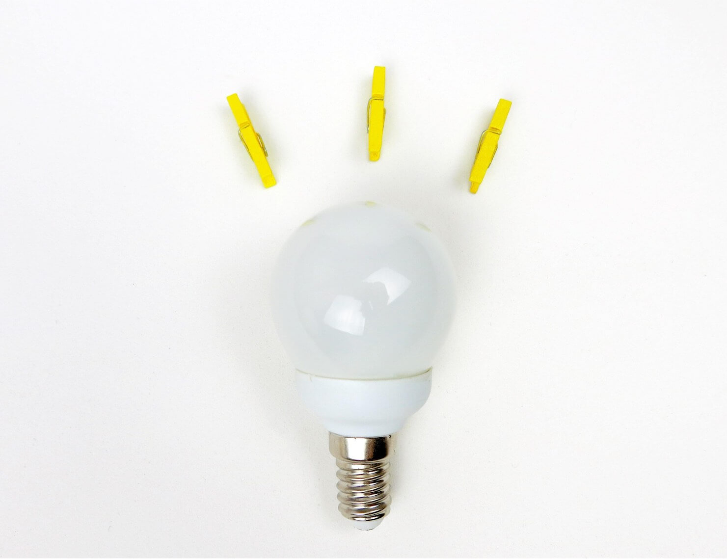 A light bulb on a white background, yellow pegs used to represent the light coming from the bulb.