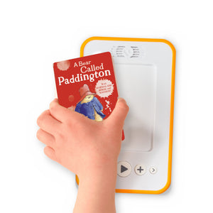 A hand holding the audiobook card for A Bear Called Paddington beside a Voxblock audiobook player