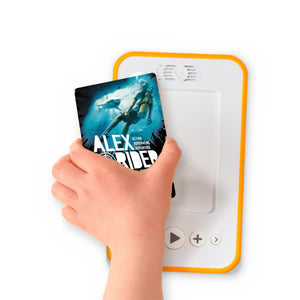 A hand holding the audiobook card for Alex Rider : Skeleton Key beside a Voxblock audiobook player