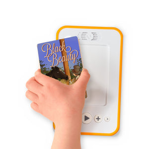A hand holding the audiobook card for Black Beauty beside a Voxblock audiobook player