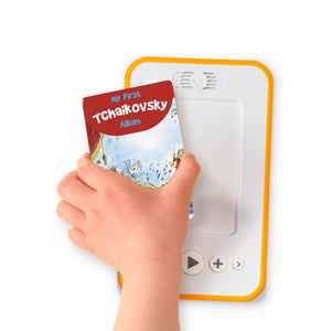 A hand holding the audiobook card for My First Tchaikovsky Album beside a Voxblock audiobook player