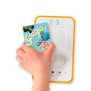 A hand holding the audiobook card for Sergio the Snail: Eco-Agent beside a Voxblock audiobook player