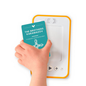 A hand holding the audiobook card for The Brothers Karamazov beside a Voxblock audiobook player