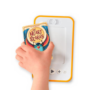 A hand holding the audiobook card for The Heart Scarab beside a Voxblock audiobook player