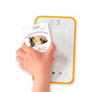 A hand holding the audiobook card for The House At Pooh Corner beside a Voxblock audiobook player