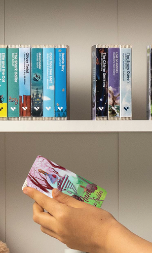 A hand taking the Anne of Green Gables audiobook from a shelf of Voxblock audiobooks