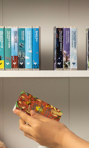 A hand taking the King Arthur & the Knights of the Round Table audiobook from a shelf of Voxblock audiobooks