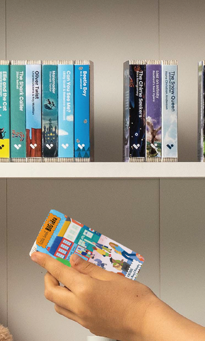 A hand taking the Little Book Big Idea audiobook from a shelf of Voxblock audiobooks