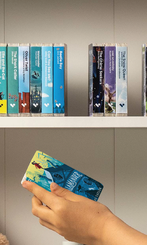 A hand taking the Malamander audiobook from a shelf of Voxblock audiobooks