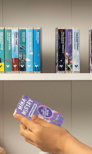 A hand taking the Mina Mistry Investigates: The Case of the Disappearing Pets audiobook from a shelf of Voxblock audiobooks