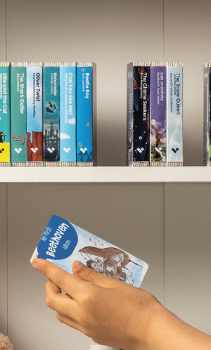 A hand taking the My First Beethoven Album audiobook from a shelf of Voxblock audiobooks