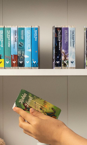 A hand taking the Robin Hood audiobook from a shelf of Voxblock audiobooks