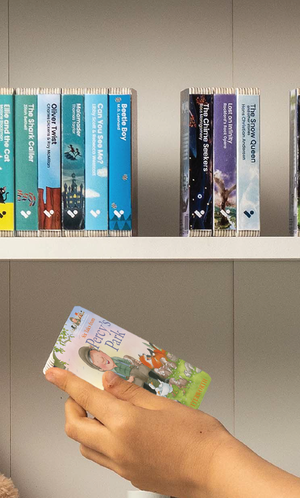 A hand taking the Six Tales From Percy’s Park audiobook from a shelf of Voxblock audiobooks