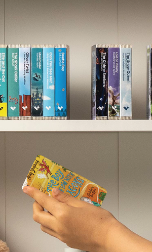 A hand taking The Boy Who Flew With Dragons audiobook from a shelf of Voxblock audiobooks