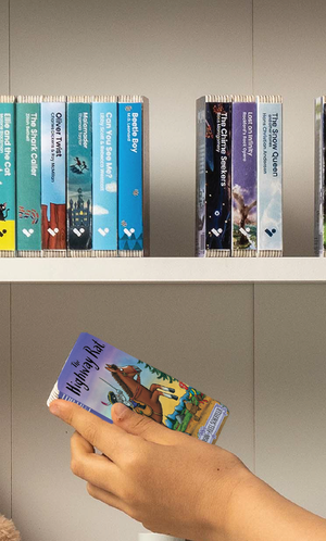 A hand taking The Highway Rat audiobook from a shelf of Voxblock audiobooks
