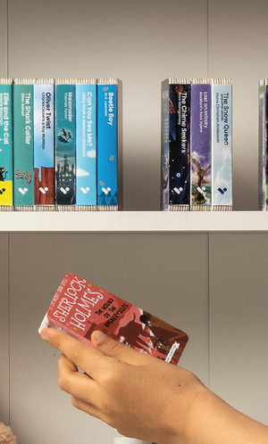 A hand taking The Hound of the Baskervilles audiobook from a shelf of Voxblock audiobooks