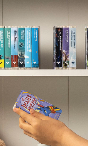 A hand taking The Jackal's Graveyard audiobook from a shelf of Voxblock audiobooks