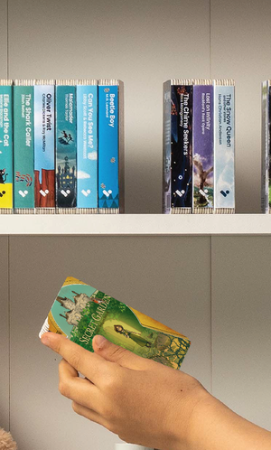 A hand taking The Secret Garden audiobook from a shelf of Voxblock audiobooks