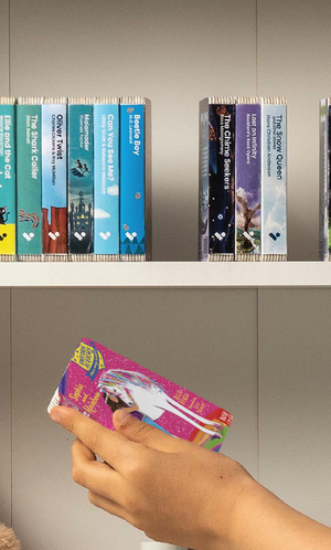 A hand taking the Unicorn Academy: Sophia and Rainbow audiobook from a shelf of Voxblock audiobooks