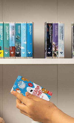 A hand taking the Wigglesbottom Primary Vol. 1 audiobook from a shelf of Voxblock audiobooks