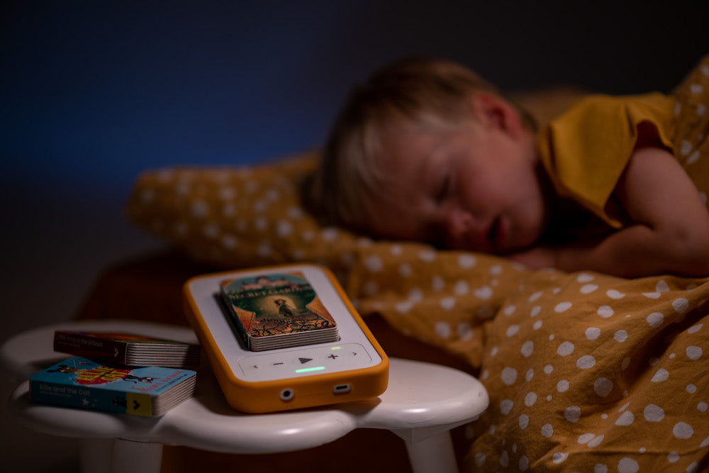 Boy sleeping next to Voxblock player