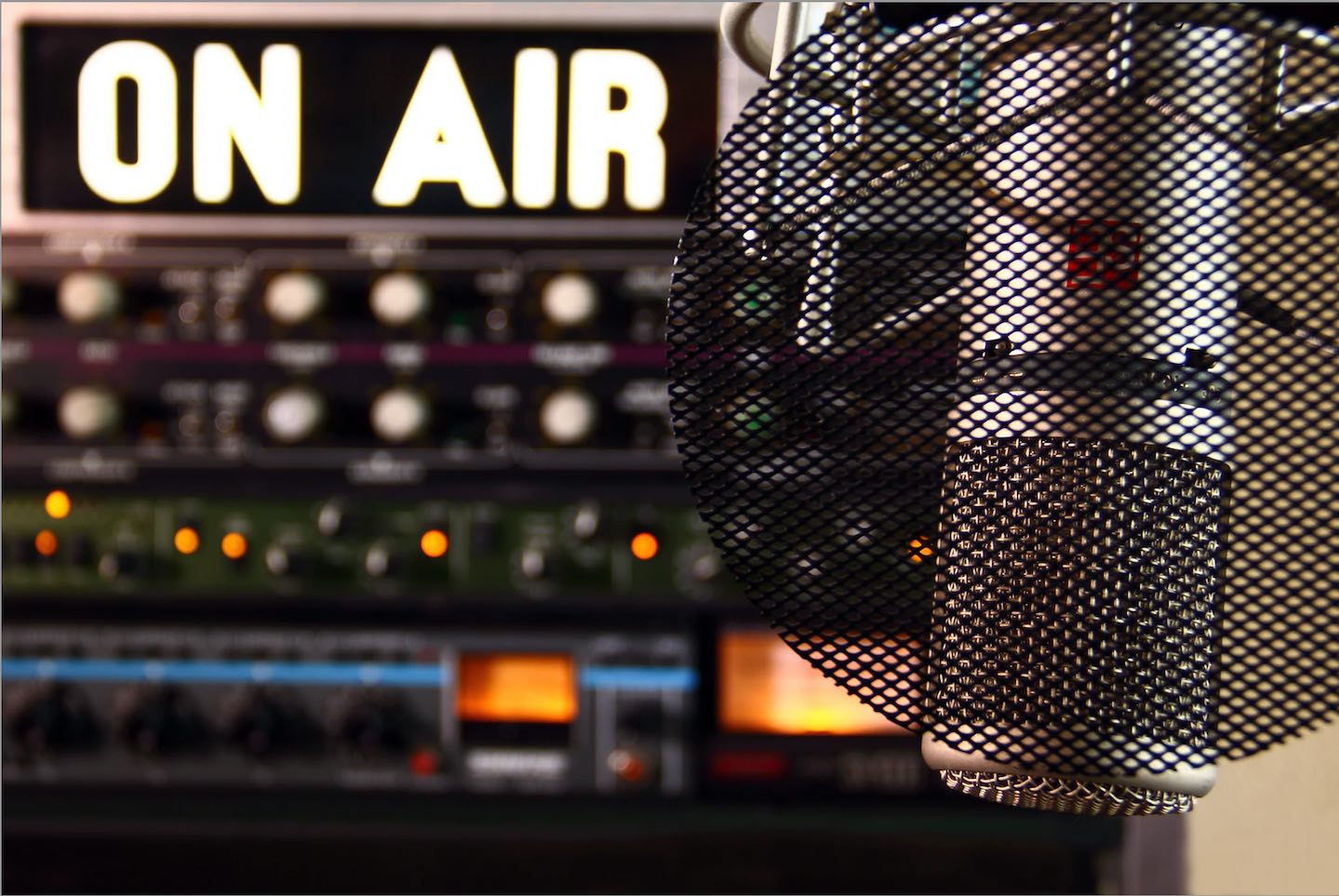 An illuminated 'on air' sign, with a microphone in the foreground.
