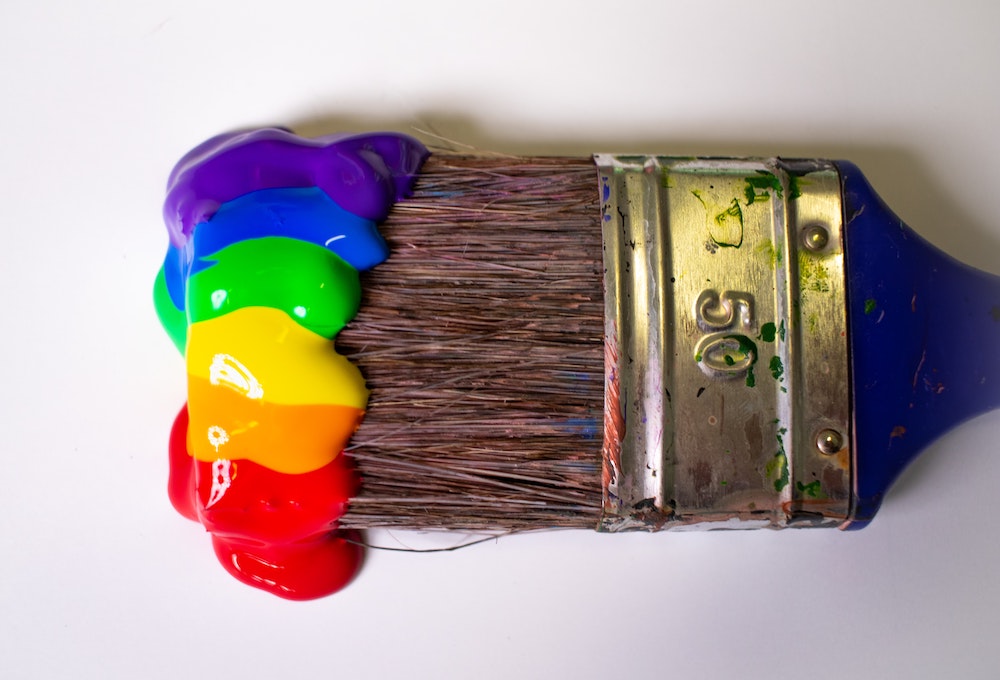 A paint brush, with paint in a rainbow array of colours.