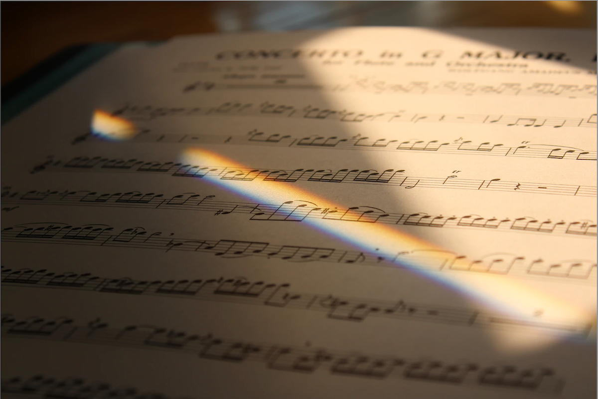 Close up of a piece of sheet music, sunlight creating a rainbow effect on the page.