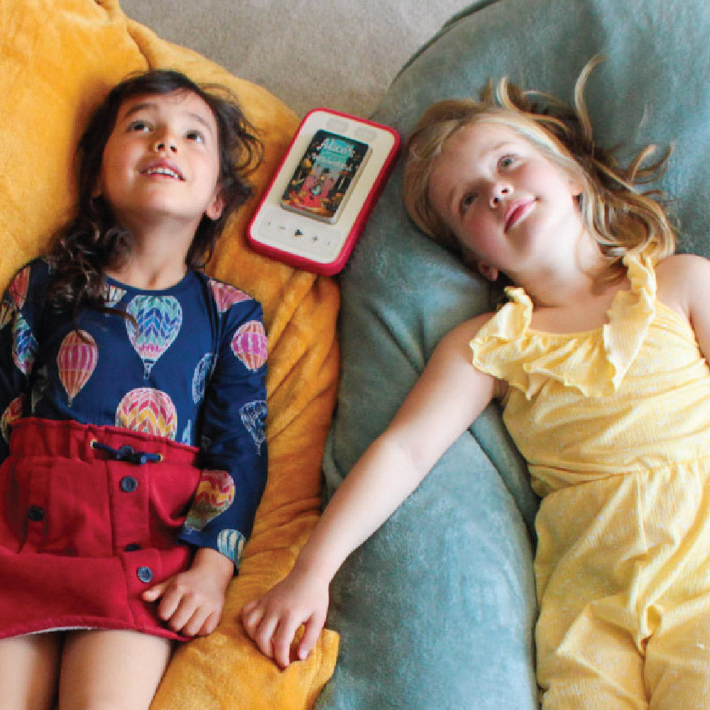 two girls relaxing listening to Alice's Adventures in Wonderland audiobook on a Voxblock screen-free audiobook player