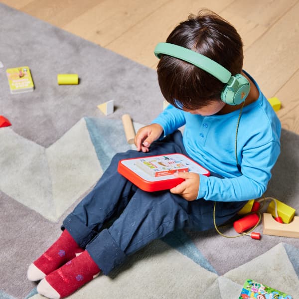 Little boy listening to a Voxblock player while sat on floor