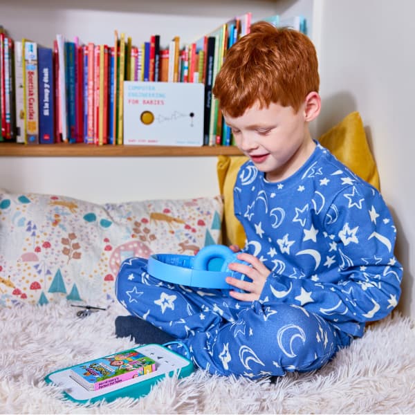 boy sitting on bed wearing pyjamas listening to an audiobook