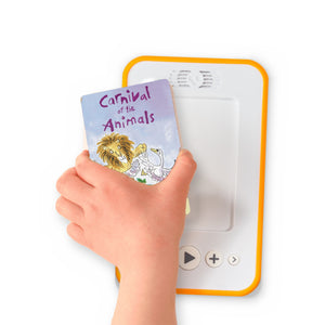 A hand holding the audiobook card for Carnival of the Animals and Other Stories beside a Voxblock audiobook player