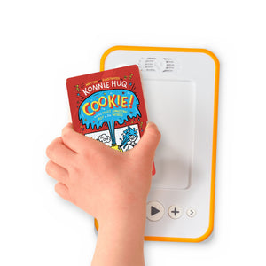 A hand holding the audiobook card for Cookie! And the Most Annoying Boy in the World beside a Voxblock audiobook player