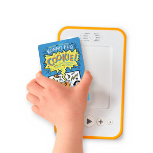 A hand holding the audiobook card for Cookie! And the Most Mysterious Mystery in the World beside a Voxblock audiobook player