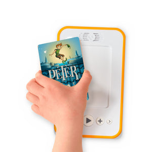 A hand holding the audiobook card for Peter Pan beside a Voxblock audiobook player