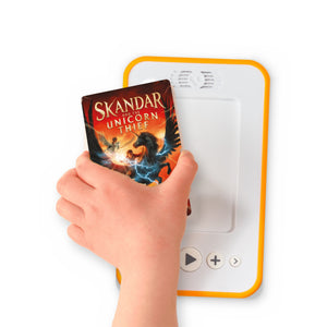 A hand holding the audiobook card for Skandar and the Unicorn Thief beside a Voxblock audiobook player