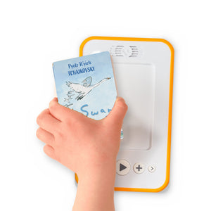 A hand holding the audiobook card for Swan Lake beside a Voxblock audiobook player