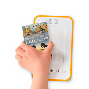 A hand holding the audiobook card for The Adventures of Tom Sawyer beside a Voxblock audiobook player