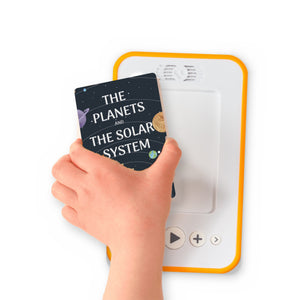 A hand holding the audiobook card for The Planets and The Solar System beside a Voxblock audiobook player