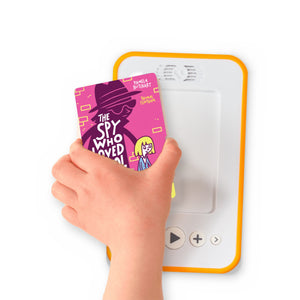 A hand holding the audiobook card for The Spy Who Loved School Dinners beside a Voxblock audiobook player