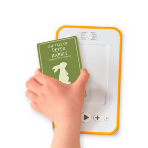 A hand holding the audiobook card for The Tale of Peter Rabbit and Other Stories beside a Voxblock audiobook player