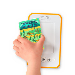 A hand holding the audiobook card for The Wonderful Wizard of Oz beside a Voxblock audiobook player