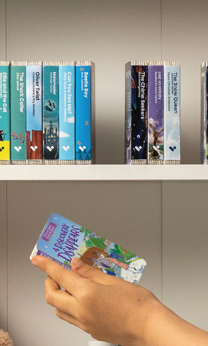 A hand taking A Discovery Disappears audiobook from a shelf of Voxblock audiobooks