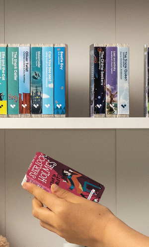 A hand taking A Study in Scarlet audiobook from a shelf of Voxblock audiobooks