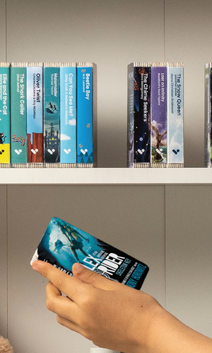A hand taking the Alex Rider : Skeleton Key audiobook from a shelf of Voxblock audiobooks