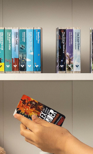 A hand taking the Alex Rider: Stormbreaker audiobook from a shelf of Voxblock audiobooks